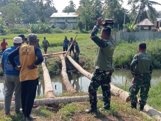 
					Wujudkan Akses Transportasi Warga, Anggota Koramil 13/Baktiya Bersama  Masyarakat Bangun Jembatan Darurat